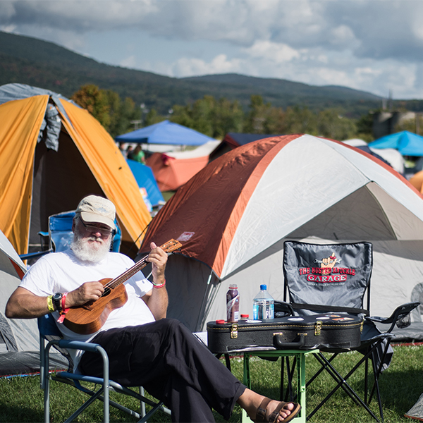 FreshGround feature image Man in front of tents playing guitar