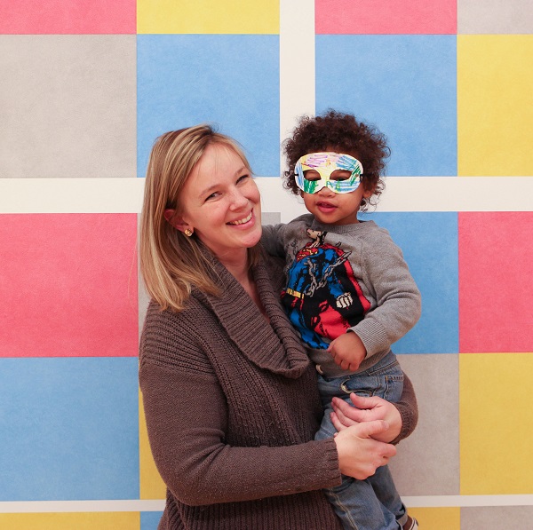 Woman holding a young boy in front of Sol LeWitt