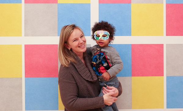 Woman holding a young boy in front of Sol LeWitt