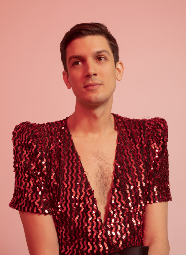 Comedian Josh Sharp in a sequin top against a pink background