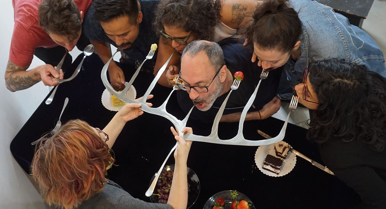 Studios at MASS MoCA resident during performance, feeding people using a multi pronged fork
