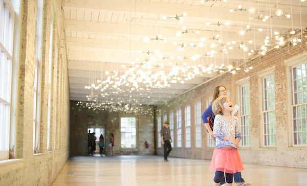 Little girl smiling while looking up at light installation