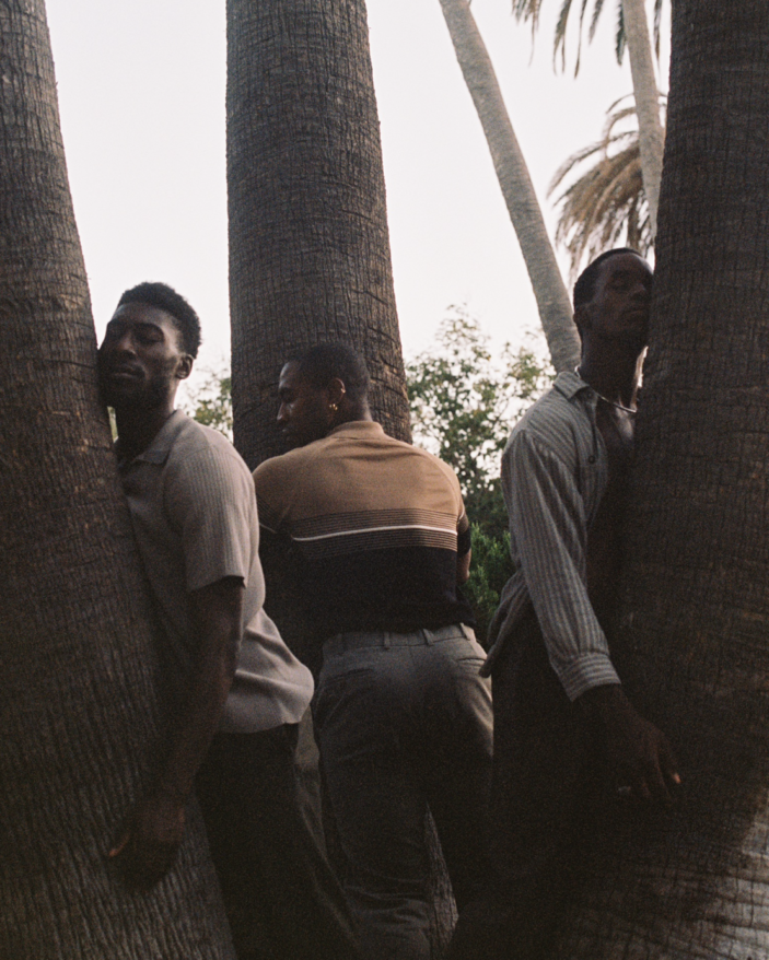 Clifford Prince King, us, you and me. Three black men leaning against palm tree