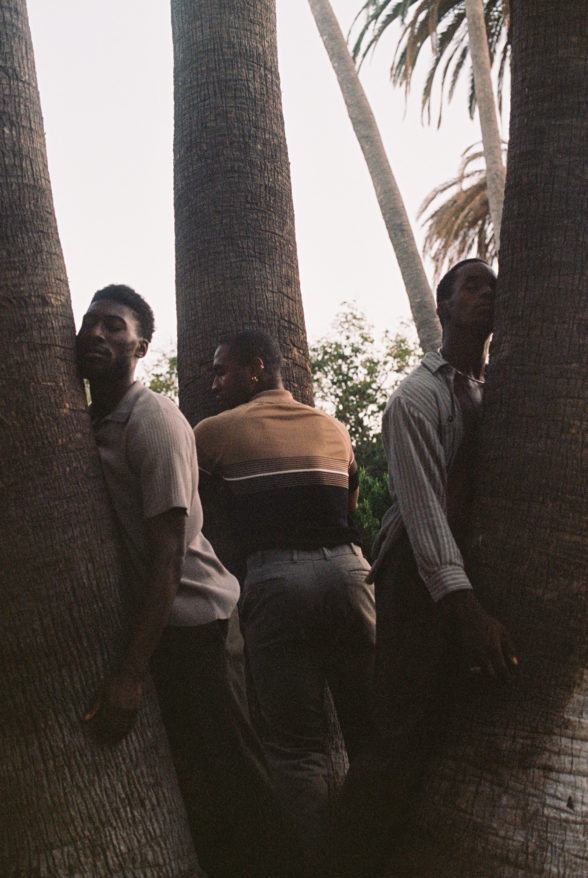 Clifford Prince King us, you and me, 2021. Image of three men leaning against tropical trees