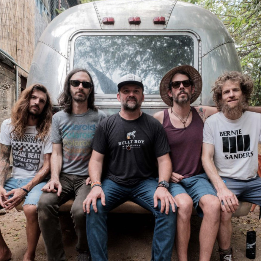 FreshGrass Lineup Announce feature image, Dispatch band members sitting on the back of an airstream trailer
