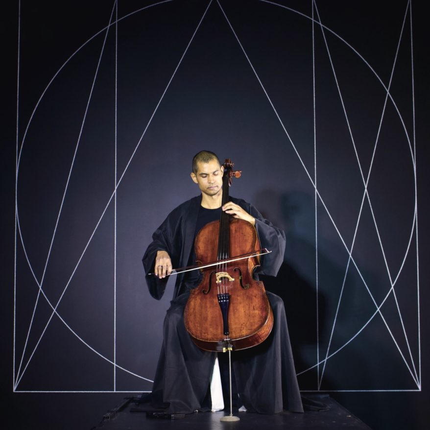 Zodiac feature image, man playing cello in front of a Sol LeWitt