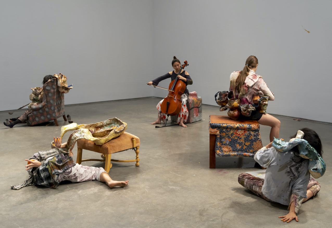 Ceramics in the Expanded Field feature image, Jennifer Jackson Hutchins performance, woman playing cello on sculpture while others move around her
