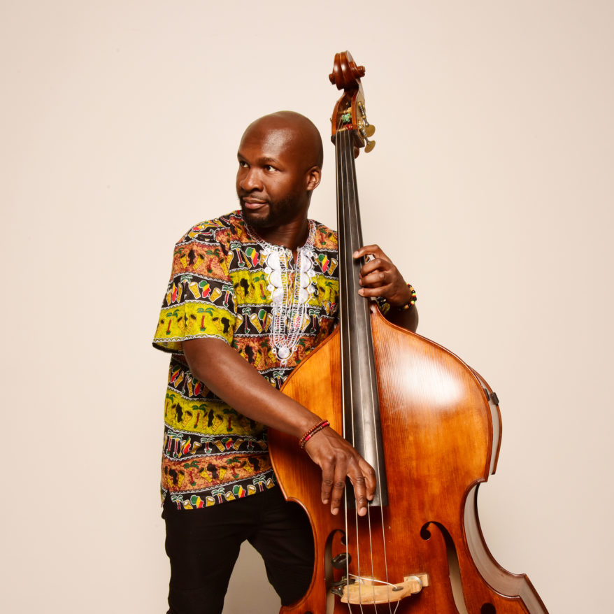 Michael Olatuja feature image, Michael Olatuja playing the bass against white background
