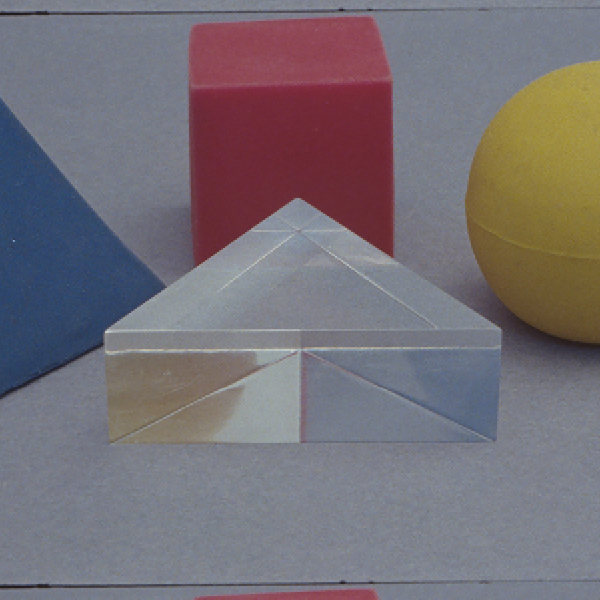 Yto Barrada feature image, Tree Identification for Beginners ( film still), picturing blue pyramid, red cube, yellow sphere, and clear triangle next to each other